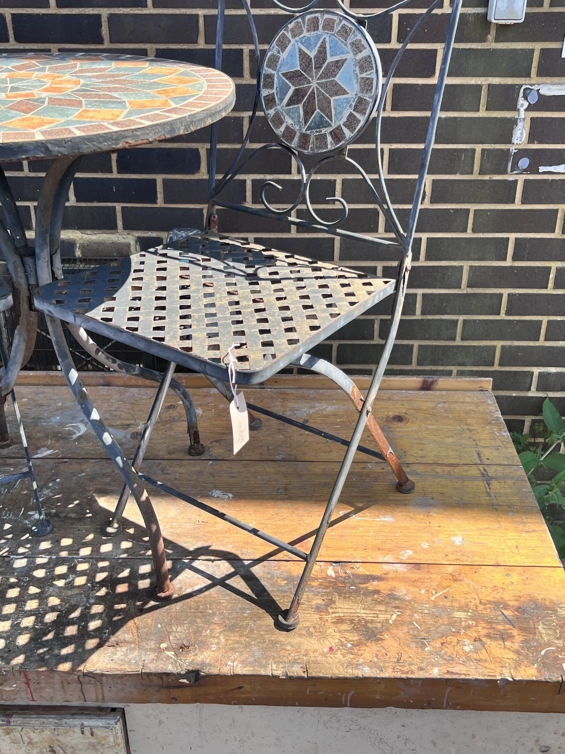 A circular mosaic topped garden table, diameter 60cm, height 73cm, and a pair of matching folding chairs